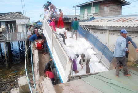 Workers begin removing bags of salt from the overweight truck so that they can eventually pull the truck out and repair the bridge.